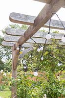 Chains of lights hanging from underside of wooden pergola
