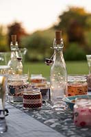 Glass bottles with light chains inside used as table decoration for evening garden party
