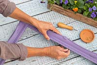 Woman fixing an eyelet to the side of painted purple picture frame