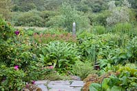 Decorative metal obelisk feature amongst dramatic summer planting with Welsh countryside beyond