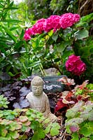 Herbaceous border with small Buddha statue