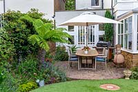 Small garden with circular artificial lawn, view towards house, patio area  with garden furniture