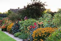 The Warm Border at Bourton House, Moreton-in-Marsh in August including Helenium 'Sahin's Early Flowerer', Dahlia 'Bishop of Llandaff', Kniphofia 'Mango Popsical' and tiger lilies.