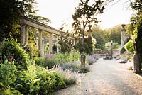 View along wide path with border and colonnade at sunset