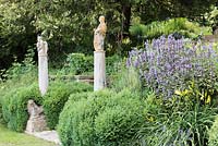 A marble lion below columns topped by Sienese saints from the 15th century, arising from mature shrubby Salvia rosmarinus - Rosemary - with Salvia - Sage nearby 