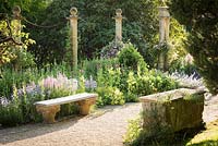 Stone benches either side of path, one on column capitals and another a Roman sarcophagus