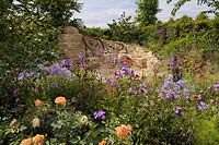 Dry stone seating area and herbaceous border with plants including, Echinacea, Phlox, Campanula, Cirsium rivulare, Rosa 'Lady of Shalott' - Zoflora.