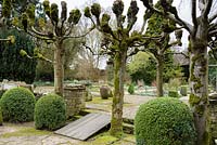 Pleached limes and clipped box framing a view into the Leisure Garden at Rodmarton Manor, Glos in February