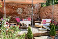 Raised seating area with shade cover, lounge furniture, wall decoration and pots