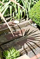 Shadows from planting on railway sleeper steps with metal grids