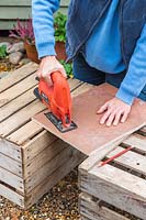 Woman using an electric jigsaw for cutting the ciruclar wooden disk