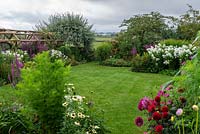 Looking out from a half-acre country garden over dahlias, lawns and borders of summer perennials, to a rural vista of Blackmore Vale with fields, spinneys and distant hills.
