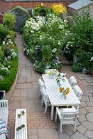 Bird's eye view of a small town garden, with dining and seating areas and white-themed borders. 