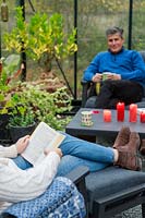 Father and daughter relaxing in lounge furniture in a greenhouse