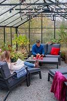 Father and daughter relaxing on lounge furniture in a greenhouse, view of rood with suspended lighting