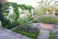 Potager with clipped box-edged beds of herbs, Rosa Wisteria Vitis and Malus. 