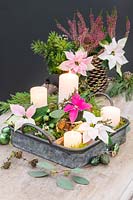 Metal tray advent arrangement with white pillar candles, poinsettia flowers. cones, moss and baubles