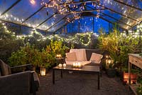 Lounge furniture inside greenhouse decorated for Christmas with fairy lights and candles