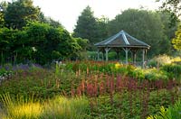 Astilbe chinensis tacqetii 'Purplelanze', Helenium atumnale 'Rubinzwerg' and grasses at sunrise in the Millenium Garden at Pensthorpe Natural Park, Fakenham, Norfolk, UK