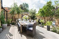 Dining table dressed for alfresco dining, on wooden deck in courtyard