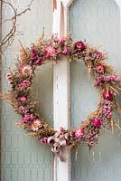 Dried flower wreath displayed on old door with everlasting flowers and sea lavender