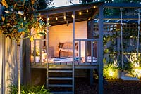 Illuminated playhouse with candles, cushions and the blanket at night in summer.