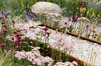 Achillea Corten steel water trough water feature filled with white pebbles. Business and Pleasure Garden, RHS Tatton Park Flower Show, 2017. Designer: Jake Curley
