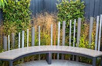 A modern garden bench on stone paved patio. The Macmillan Legacy Garden, RHS Tatton Park Flower Show, 2017. Designer: Lara Behr 