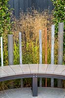A modern garden bench on stone paved patio. The Macmillan Legacy Garden, RHS Tatton Park Flower Show, 2017. Designer: Lara Behr