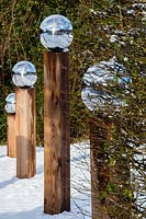 Line of wooden posts topped with stainless steel globes. Garden - Veddw 