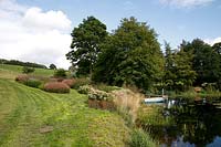 Piet Oudolf perennial planting by the lake in a private garden at Brockhampton open for NGS