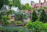 A formal kitchen garden with bespoke oak cloches to protect vulnerable crops, bay tree cones to add permanence, and an Alitex greenhouse for growing tomatoes, chilli peppers and annuals.