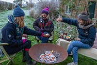 Roasting marshmallows over a fire in a Corten Steel fire pit