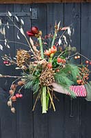 Woman holding floral arrangement with Hippeastrum, Hydrangea, Physalis, Rosehips, seedheads and Pinus - Pine foliage