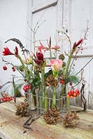 Floral arrangement in tray with milk bottles including Hippeastrum, crab apples, seedheads, holly and dried Hydrangea flowers. Styling: Marieke Nolsen