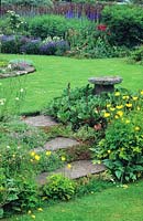 Meconopsis cambrica - Welsh poppy flowering by steps in formal garden. 
