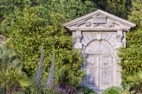 The Italian Gate carved from green oak and based on designs by Inigo Jones for Arundel House in London from the early 17th century in the Collector Earl's Garden at Arundel Castle, West Sussex in May. Framed by echiums and palms.