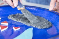 Close up of woman using a scraper to spread grout around a plate