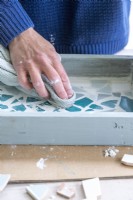 Wiping excess grout off of the surface of the mosaic