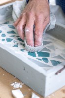Wiping excess grout off of the surface of the mosaic