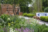 The Viking Friluftsliv Garden. A multi-stemmed amelanchier shades a bed of astrantias, penstemon, coneflowers, salvias, gaura and thalictrum. On the other side of the box-edged rill is a seating area, shaded by tall birch trees.