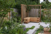 The Communication Garden. A tranquil refuge with woodland planting and native wayfaring and hazel trees. The flooring is laid in planking and gravel. Wooden screens and cubes are made from sweet chestnut.