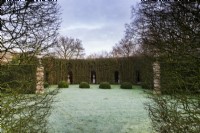 The Green Theatre on a frosty morning, recalling the Italian tradition of teatro di verzura, featuring a grassy auditorium, the 'stage' of classical urns on plinths, framed by the twiggy tracery of hornbeam, and 'footlights'  of box (Buxus sempervirens).