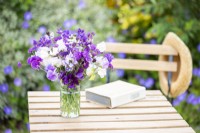 An arrangement of Nigella papillosa 'Delft Blue', Salvia viridis 'Blue Monday', Verbena rigida 'Santos', Lathyrus 'High Scent', 'Pluto' - Sweet Peas in a glass vase