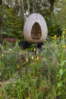 Yeo Valley Organic Garden. Naturalistic perennial meadow with pathway to focal point of steam-bent oak egg seat. Foreground planting includes Kniphofia
'Tawny King', Rudbeckia laciniata
'Herbstonne', Calamagrostis Ã—
acutiflora 'Karl Foerster', Calamagrostis
brachytricha, and various Persicarias.