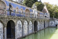 View across the Basin of the Knights pool to The Kings Gallery. Raised walkway with stone balustrade. Walls above pond decorated with full sized representations made of glazed tiles or Azulejos of  Knights on horseback. Lisbon, Portugal, September.