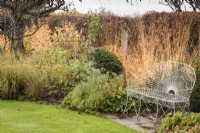 Wirework seat set into a border in a country garden in November