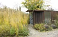 Walk-in Corten steel structure with display boards, set in border of grasses near lamp post.