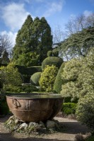 Topiary garden in early spring.  Large copper urn container as focal point