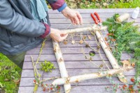 Woman fixing twigs to the frame